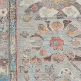 Close-up of a patterned rug with floral and animal designs on a gray background.