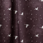 Draped fabric in a flying geese and star pattern in white on a deep eggplant purple watercolor field.