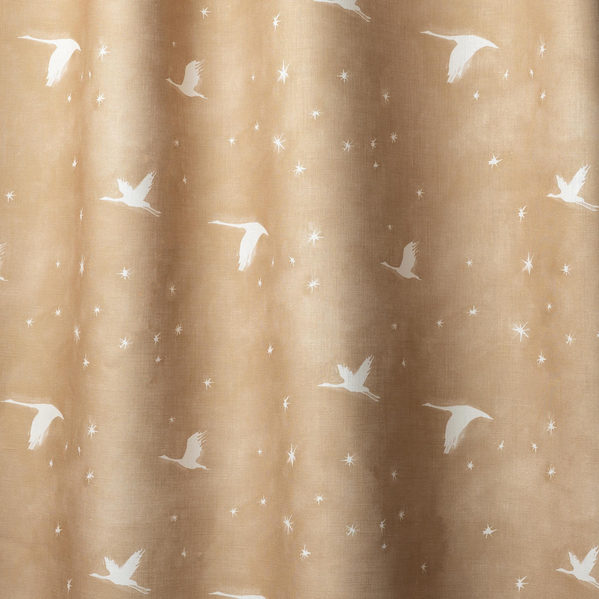 Draped fabric a flying geese and star pattern in white on a warm tan watercolor field. 
