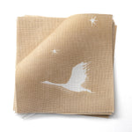Stacked fabric swatches in a flying geese and star pattern in white on a warm tan watercolor field. 