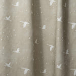Draped fabric in a flying geese and star pattern in white on a taupe watercolor field.