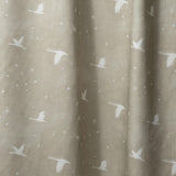 Draped fabric in a flying geese and star pattern in white on a taupe watercolor field.