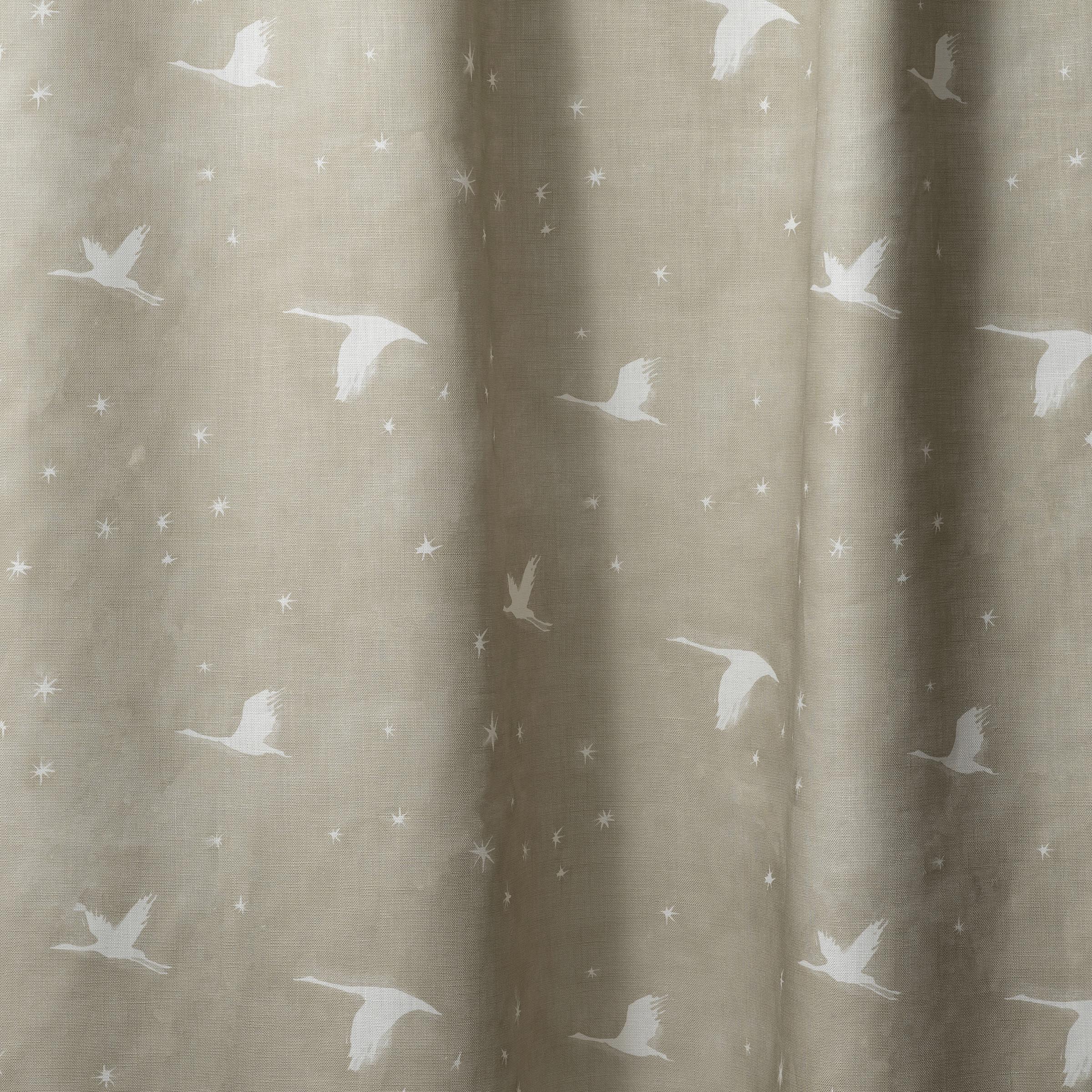 Draped fabric in a flying geese and star pattern in white on a taupe watercolor field.