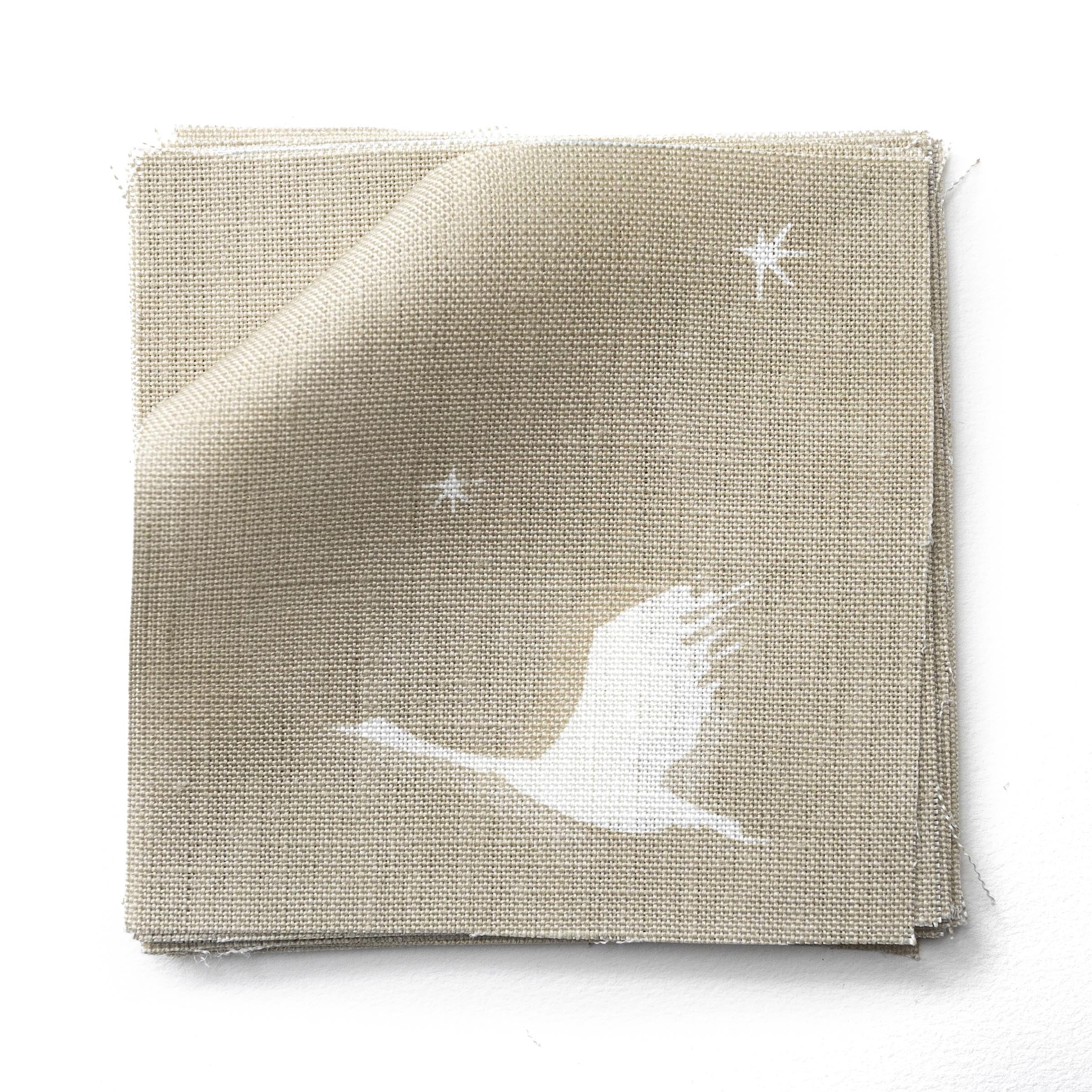 Fabric swatches in a flying geese and star pattern in white on a taupe watercolor field.