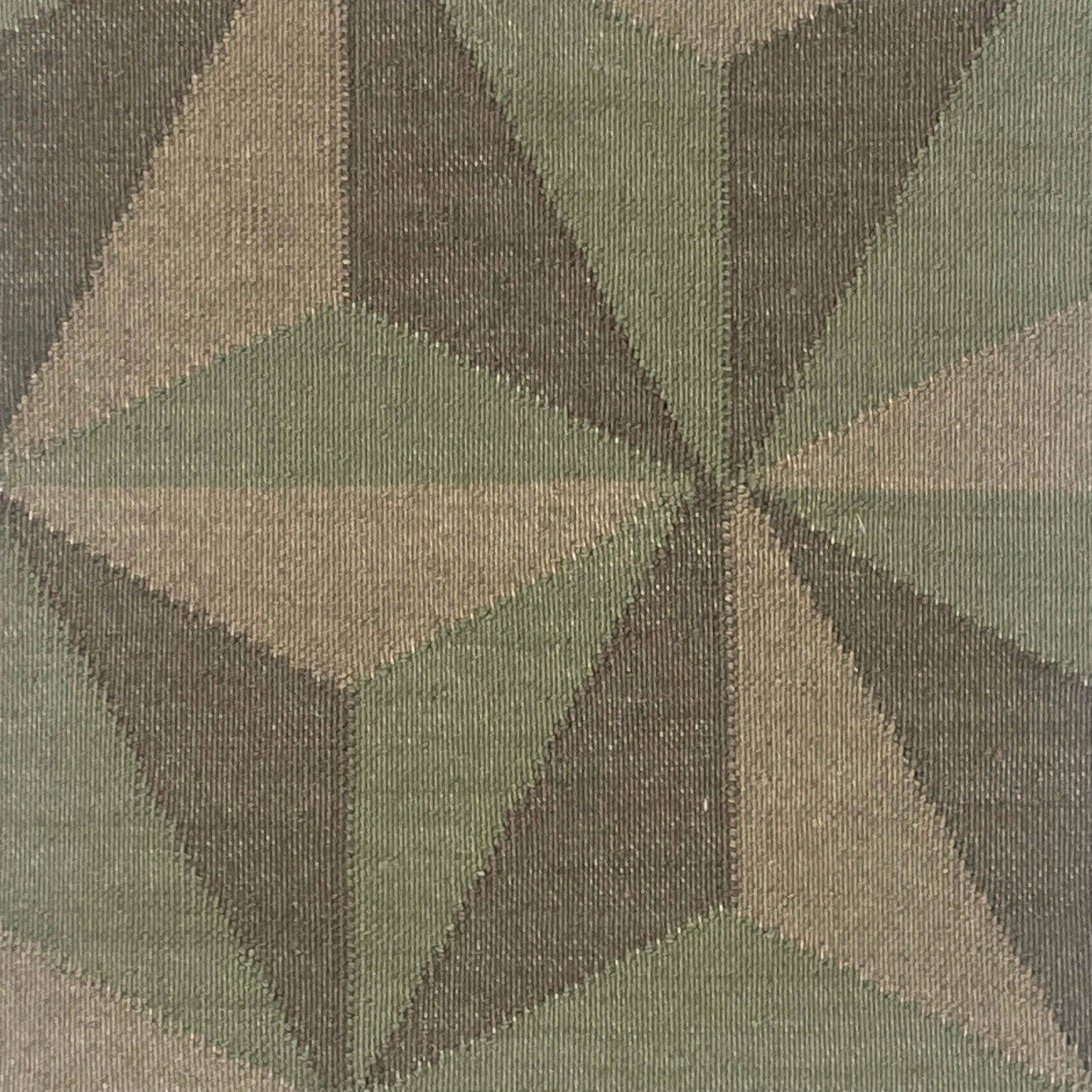 Close-up of a geometric patterned rug with shades of green, grey and brown.