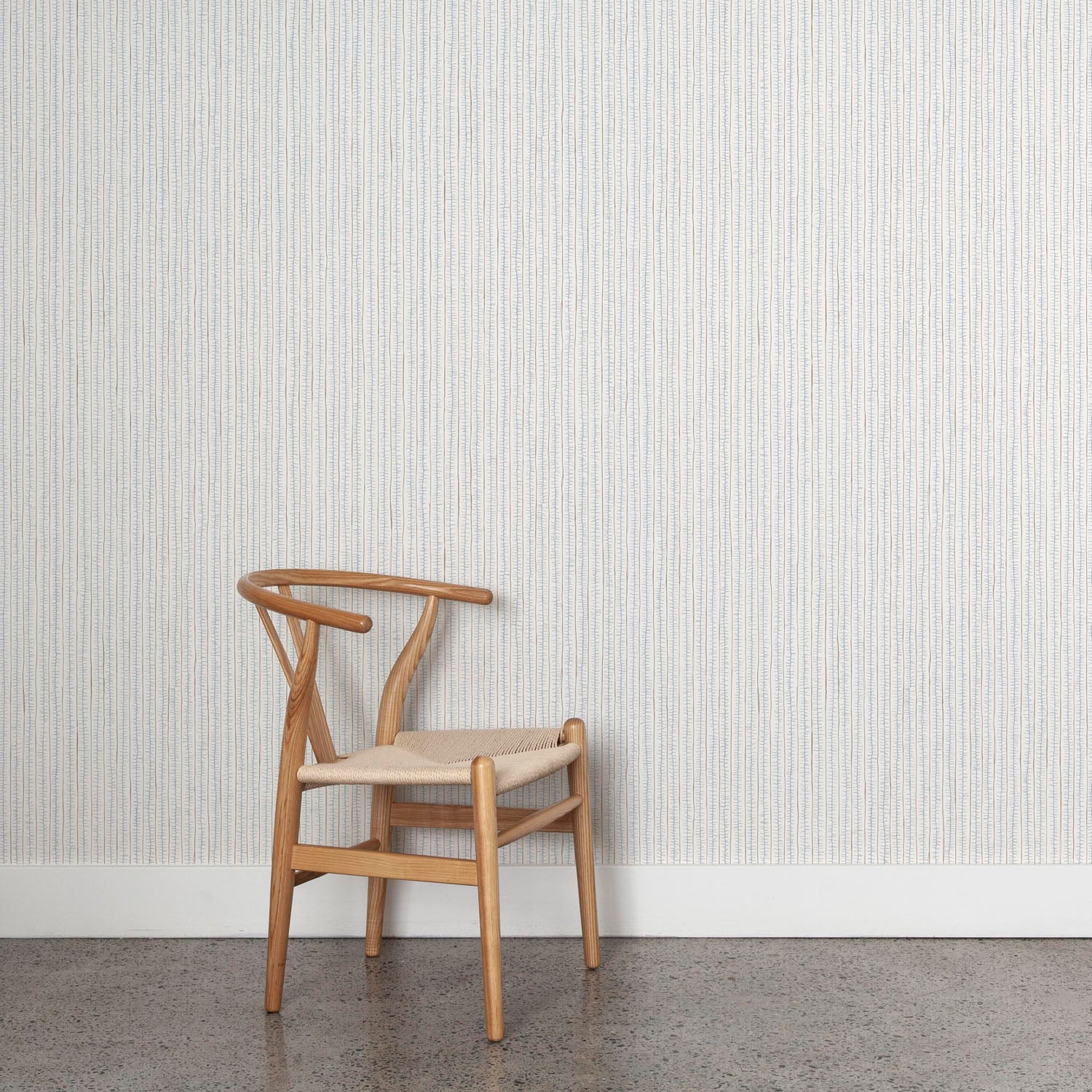 Wooden chair against wallpaper with hand drawn ticking stripe in light blue and brown on white. 