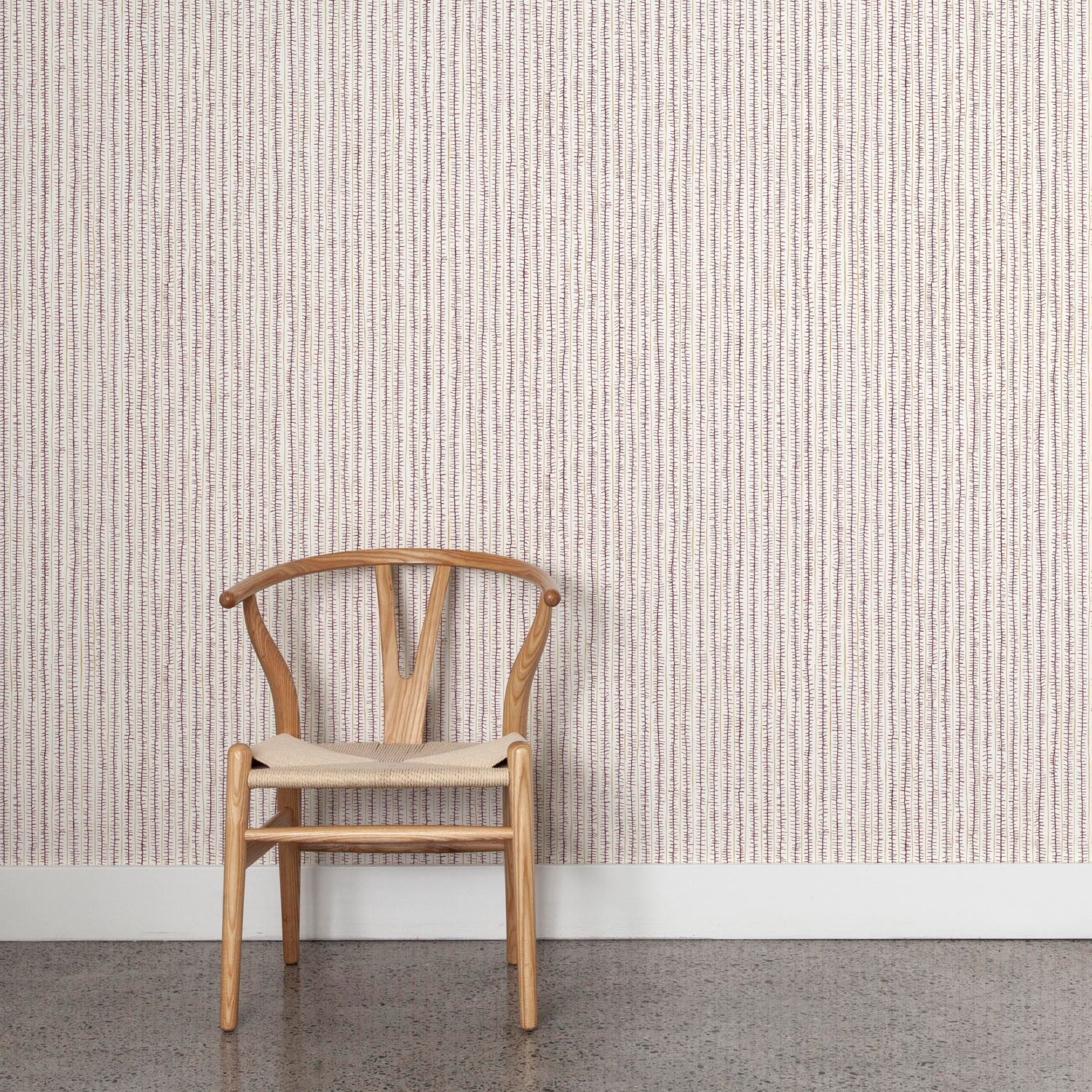Wooden chair against wallpaper with hand drawn ticking stripe in dark purple and tan on white. 