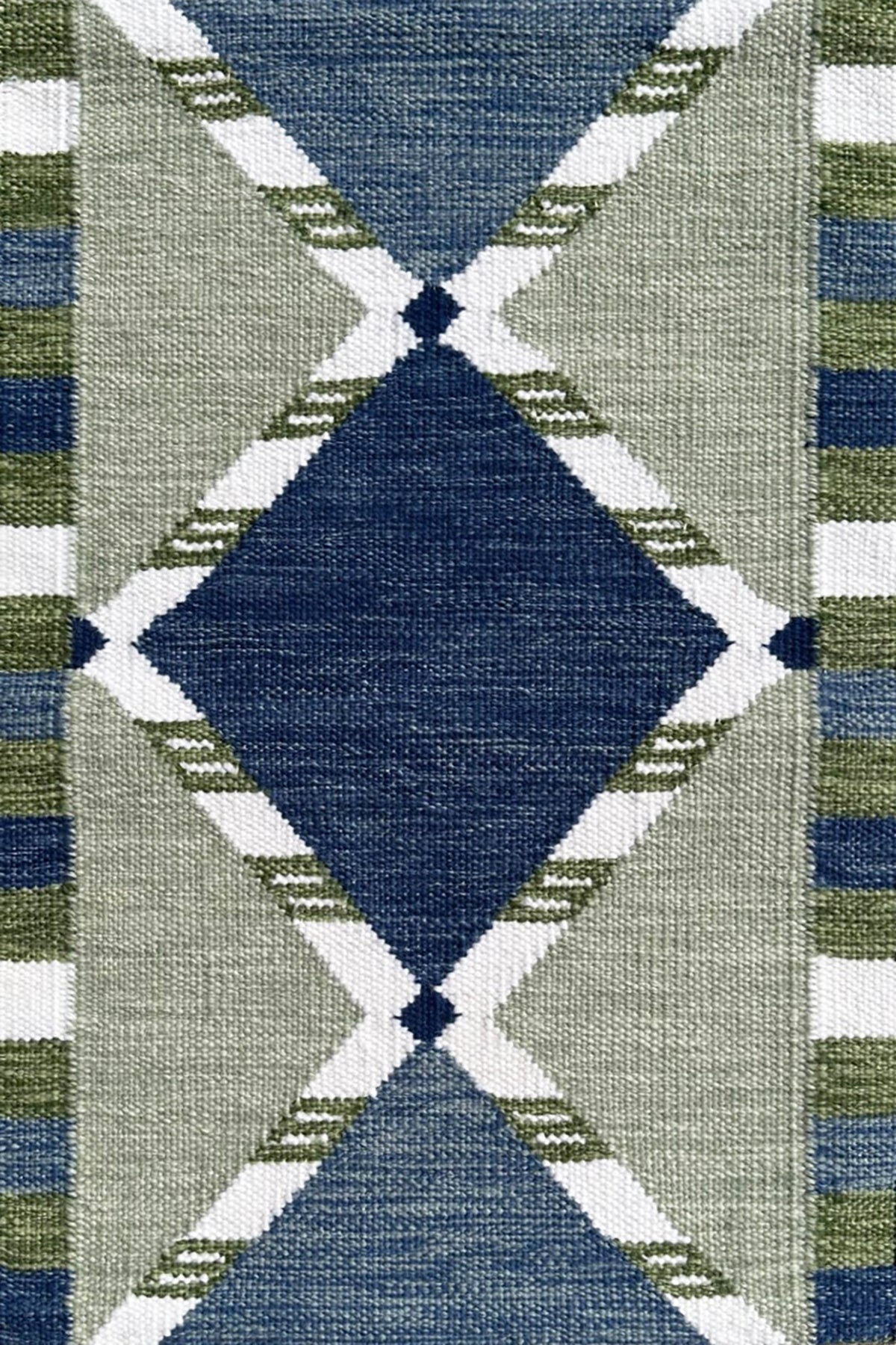 Handwoven rug detail in a Swedish diamond lattice design shades of green and blue with white accents. 