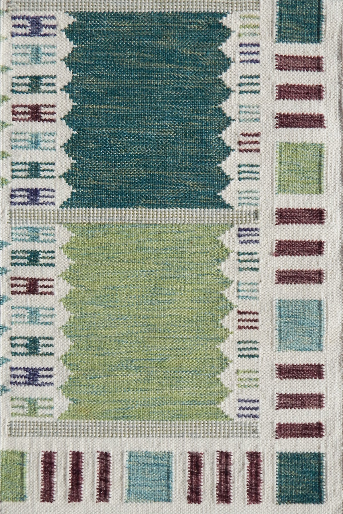 Handwoven rug detail in a Swedish checkerboard design shades of green and teal with white and brown accents. 