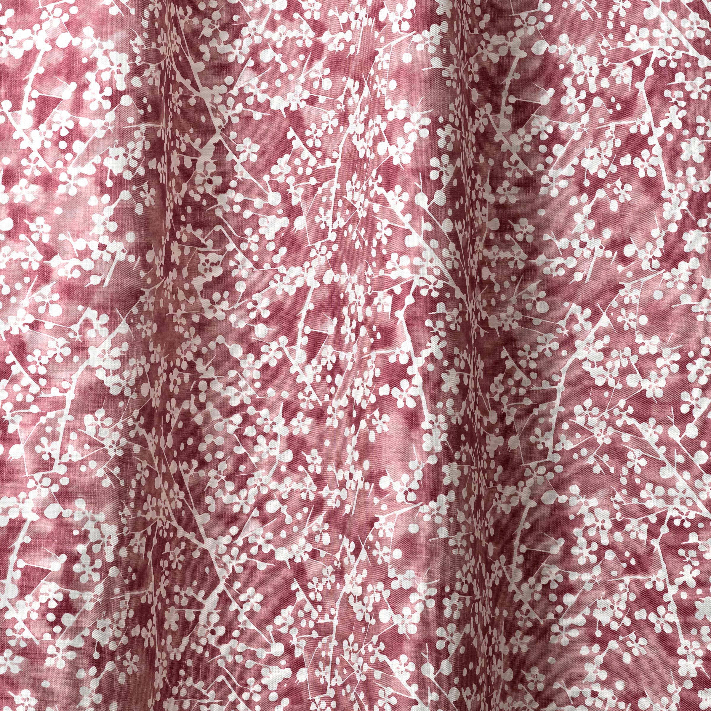 Draped fabric in a painterly branch print in white on a berry red watercolor field.