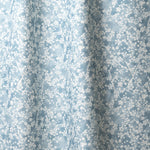 Draped fabric in a painterly branch print in white on soft blue watercolor field.