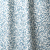 Draped fabric in a painterly branch print in white on soft blue watercolor field.