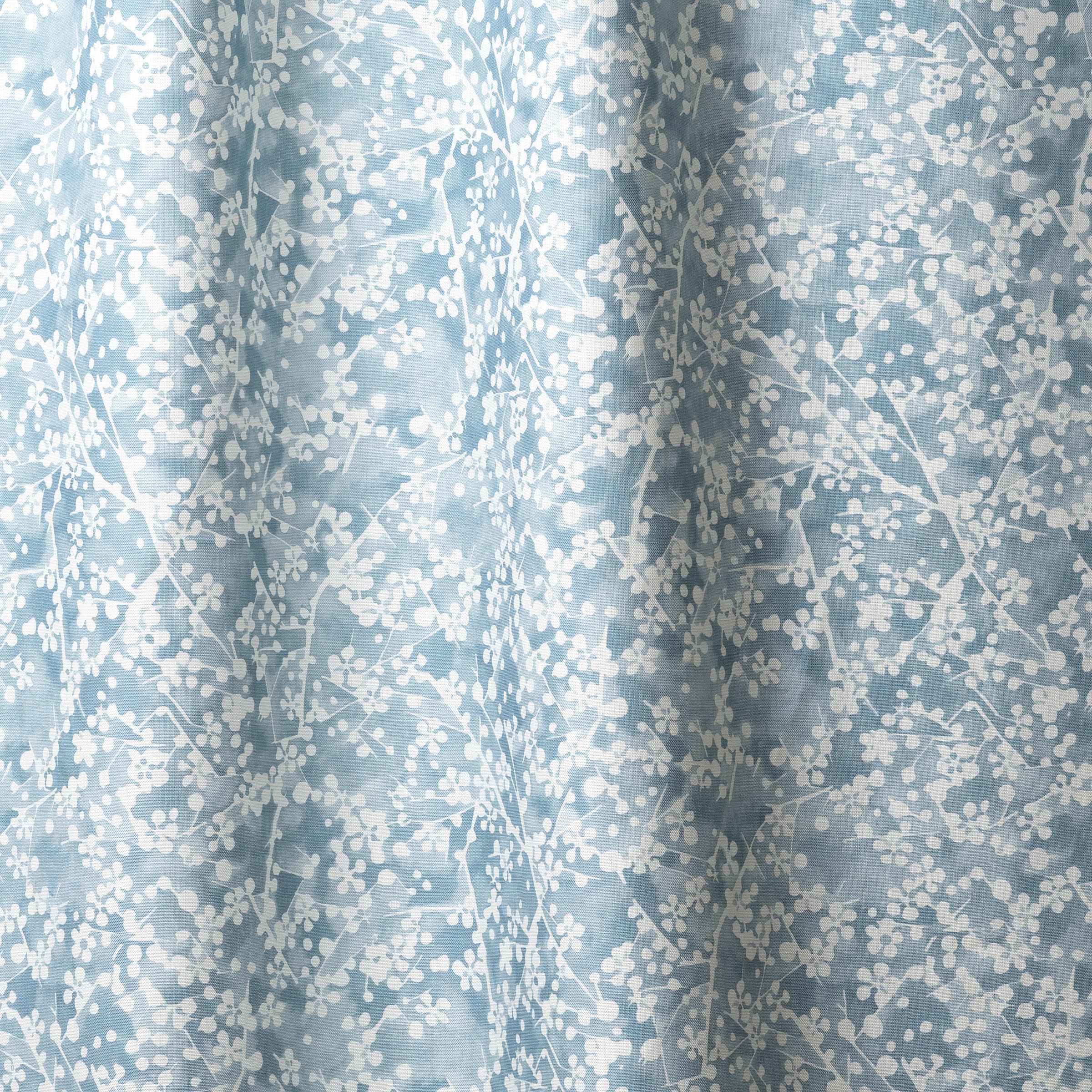 Draped fabric in a painterly branch print in white on soft blue watercolor field.
