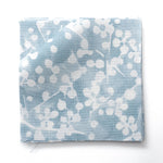 Fabric swatches in a painterly branch print in white on soft blue watercolor field.