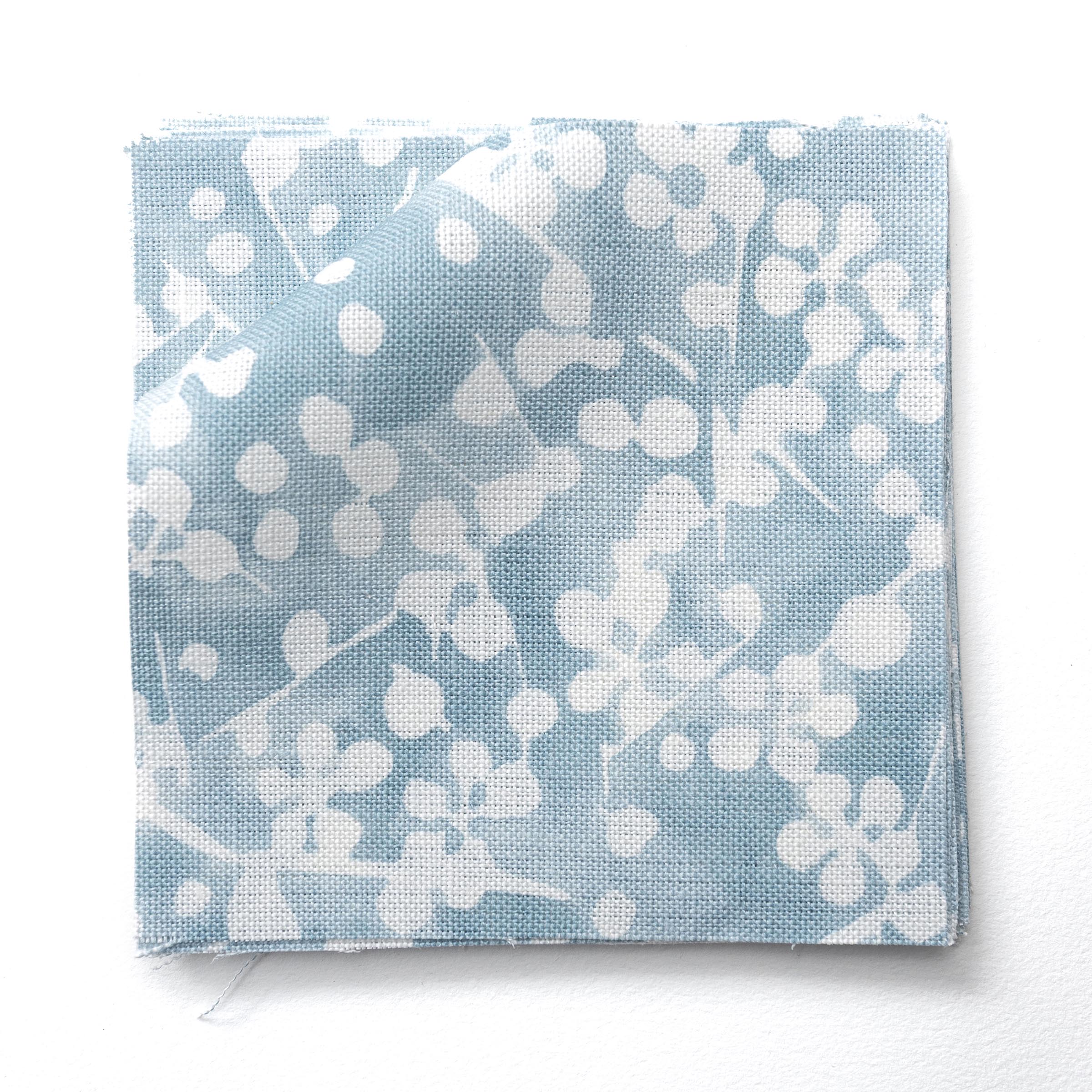 Fabric swatches in a painterly branch print in white on soft blue watercolor field.