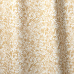 Draped fabric in a painterly branch print in white on a warm yellow watercolor field.