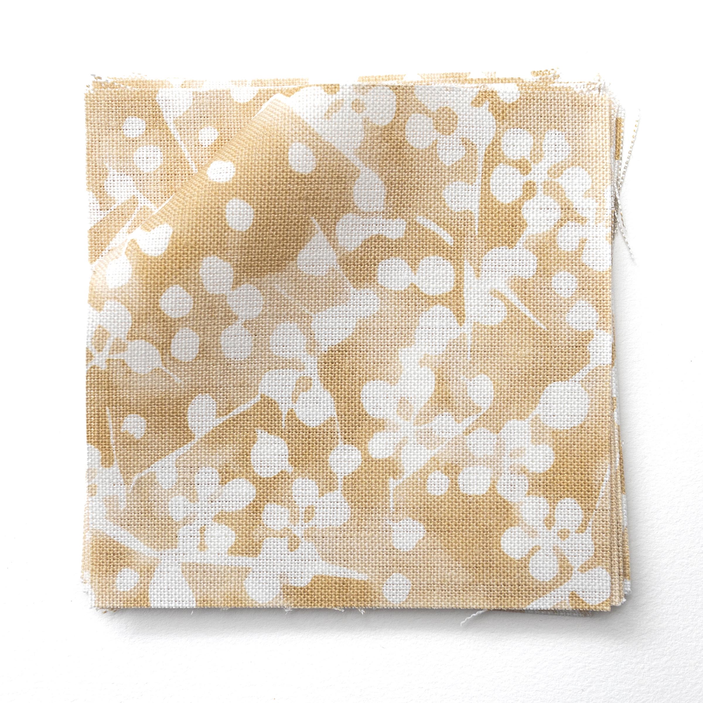 Fabric swatches in a painterly branch print in white on a warm yellow watercolor field.