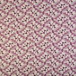 Detail of fabric in painterly diamond print in shades of purple on a white field.