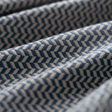 Close-up of blue and cream textured fabric with a herringbone pattern light folded. 