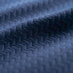 Close-up of a blue textured fabric with a herringbone pattern light folded. 