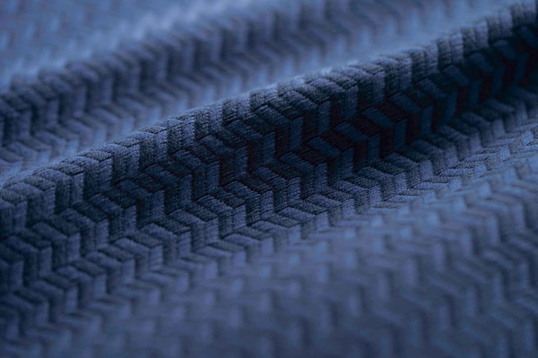 Close-up of a blue textured fabric with a herringbone pattern light folded. 