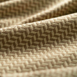 Close-up of a taupe textured fabric with a herringbone pattern light folded. 