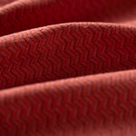 Close-up of red textured fabric with a herringbone pattern light folded. 