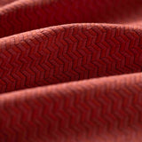 Close-up of red textured fabric with a herringbone pattern light folded. 
