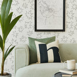Modernist living room with a sofa and plant in front of a wall papered in a cartoon "Pow" print in gray and white.
