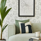 Modernist living room with a sofa and plant in front of a wall papered in a cartoon "Pow" print in gray and white.