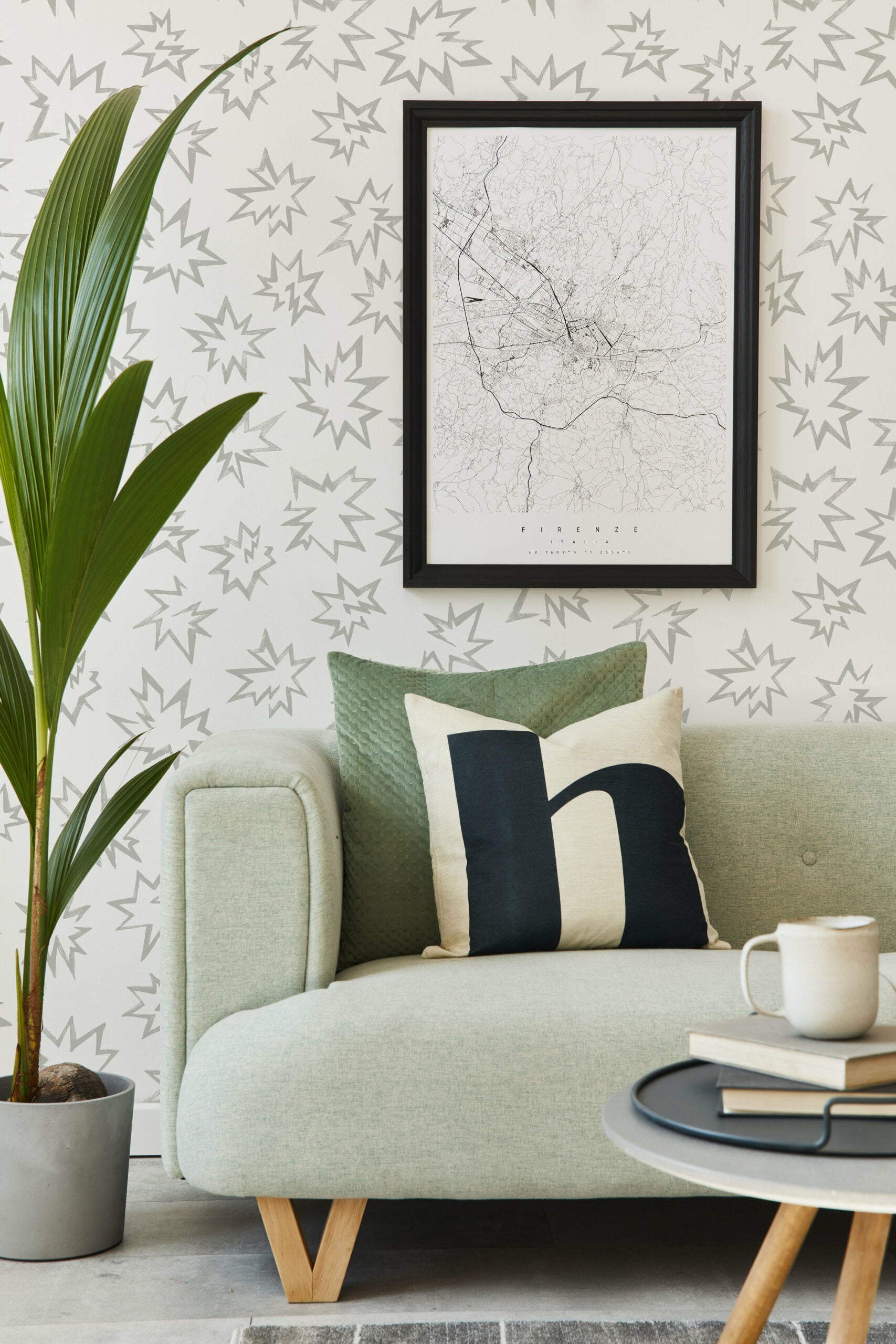 Modernist living room with a sofa and plant in front of a wall papered in a cartoon "Pow" print in gray and white.