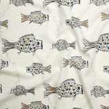 Close up of gently draped printed linen with a pattern of hand-drawn fish in navy with tan and blue scales and scattered bubble dots on white. 