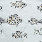 Close up of wallpaper with a pattern of hand-drawn fish in black with tan and brown scales and scattered black bubble dots on white. 