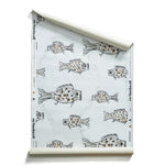 A roll of wallpaper with a white background and a pattern of hand-drawn black fish with brown spots, unrolled slightly