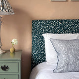 A cozy bedroom tableau with a headboard and throw pillows all upholstered in the same playful polka dot print.