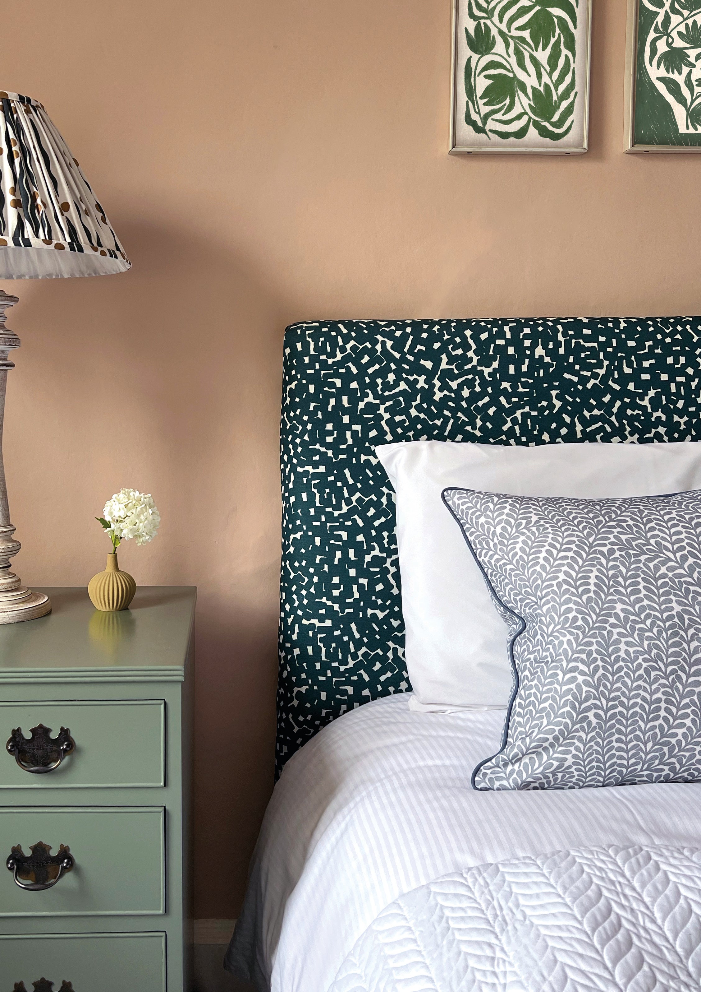 A cozy bedroom tableau with a headboard and throw pillows all upholstered in the same playful polka dot print.