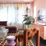 A funky modernist living room with floor-length curtains in a watercolor watercolor print in pastels on a white field.