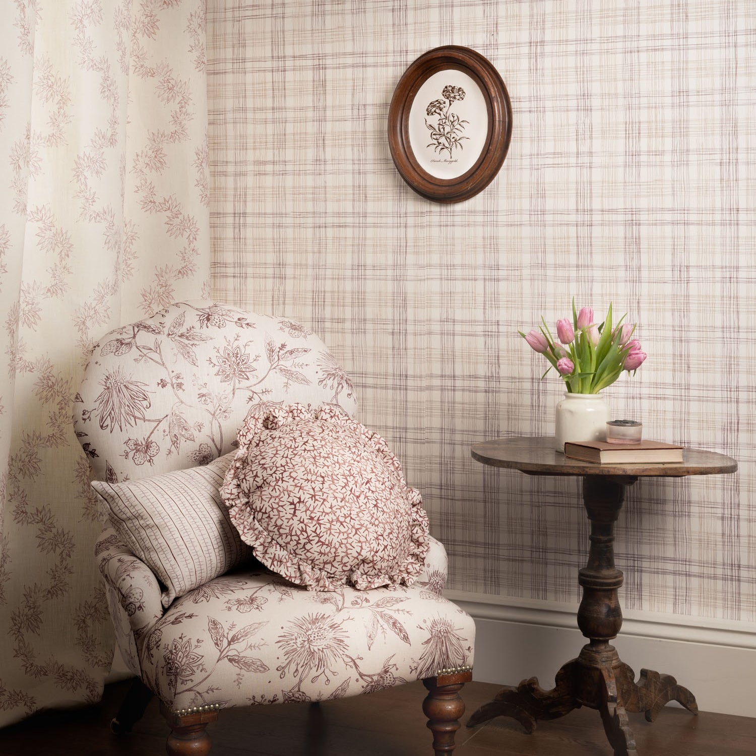 Decorative armchair with floral pattern in a room with patterned wallpaper and a small table with flowers.