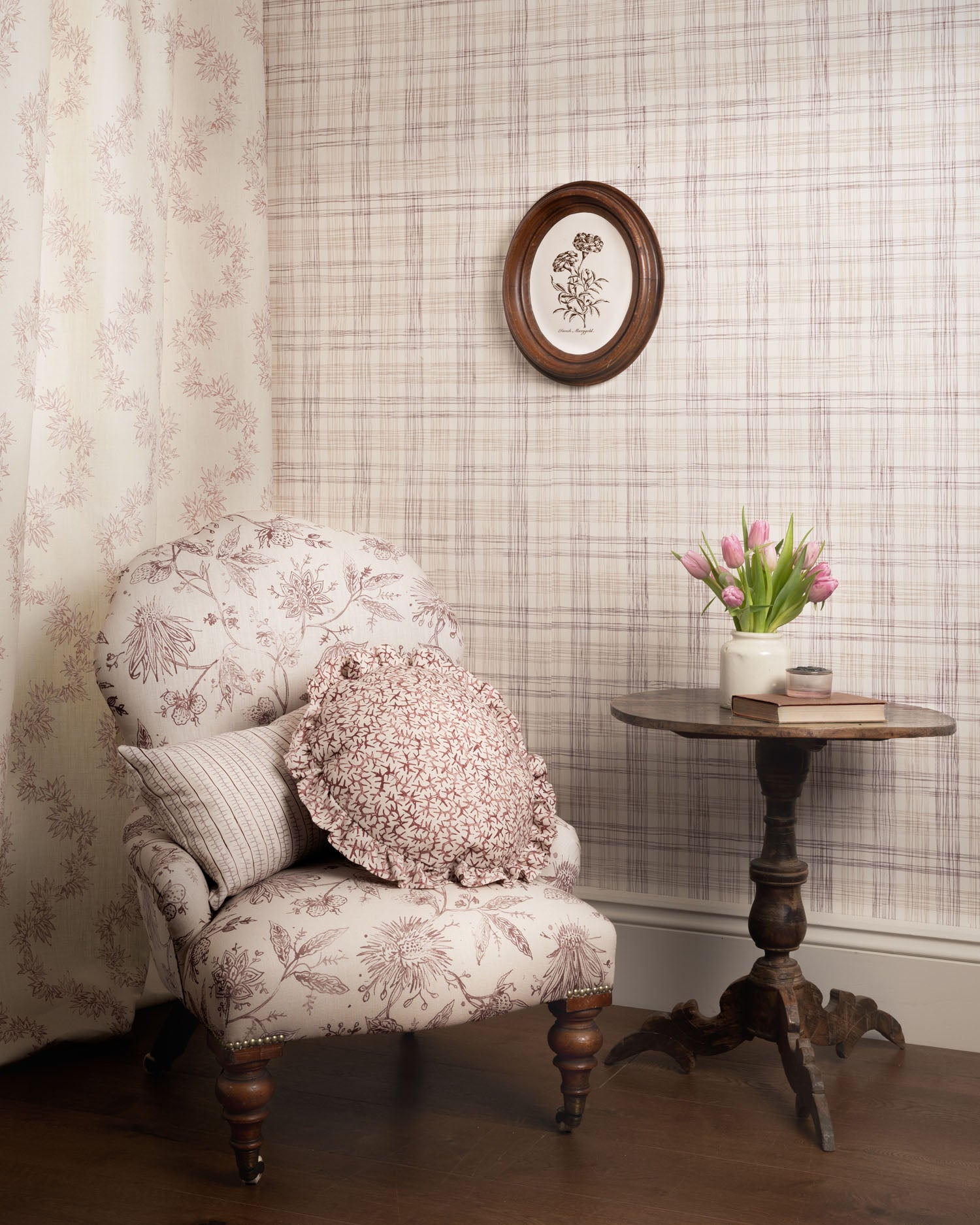 Decorative armchair with floral pattern in a room with patterned wallpaper and a small table with flowers.