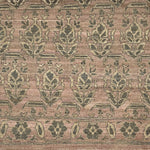 Handknotted rug with traditional floral motif in grey on a pink background. 