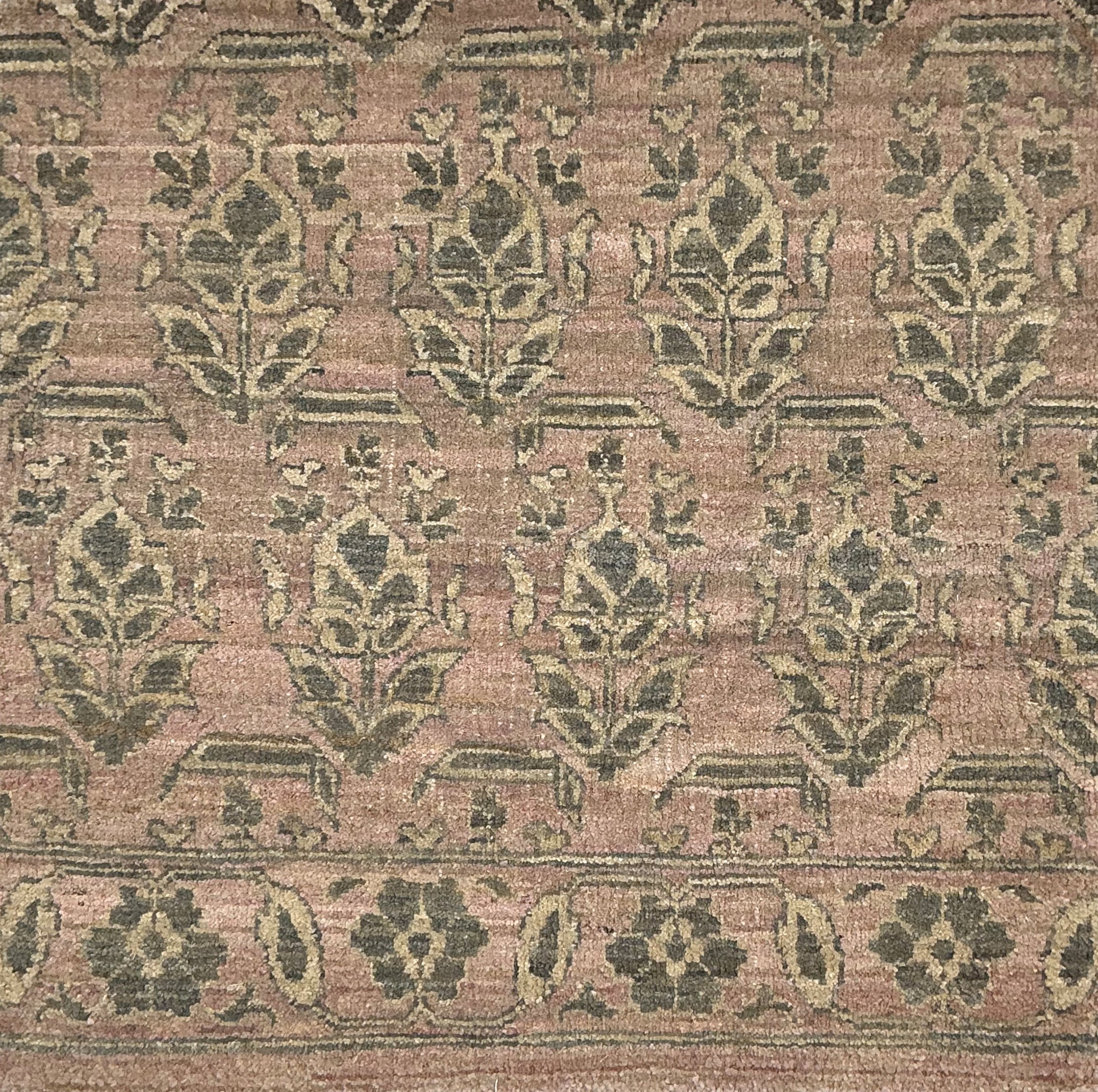 Handknotted rug with traditional floral motif in grey on a pink background. 