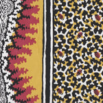 Detail of fabric in a bordered paisley print in shades of black, red, yellow and white.