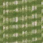 Detail of fabric in a textural shibori print in shades of green on a greige field.