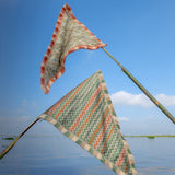 Two colorful triangular flags on a stick over a body of water with a clear blue sky.