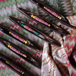 Set of wooden shuttles with colorful thread on a patterned fabric background