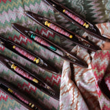 Set of wooden shuttles with colorful thread on a patterned fabric background