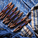 Set of wooden weaving tools with colorful threads on a patterned fabric background