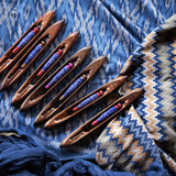 Set of wooden weaving tools with colorful threads on a patterned fabric background