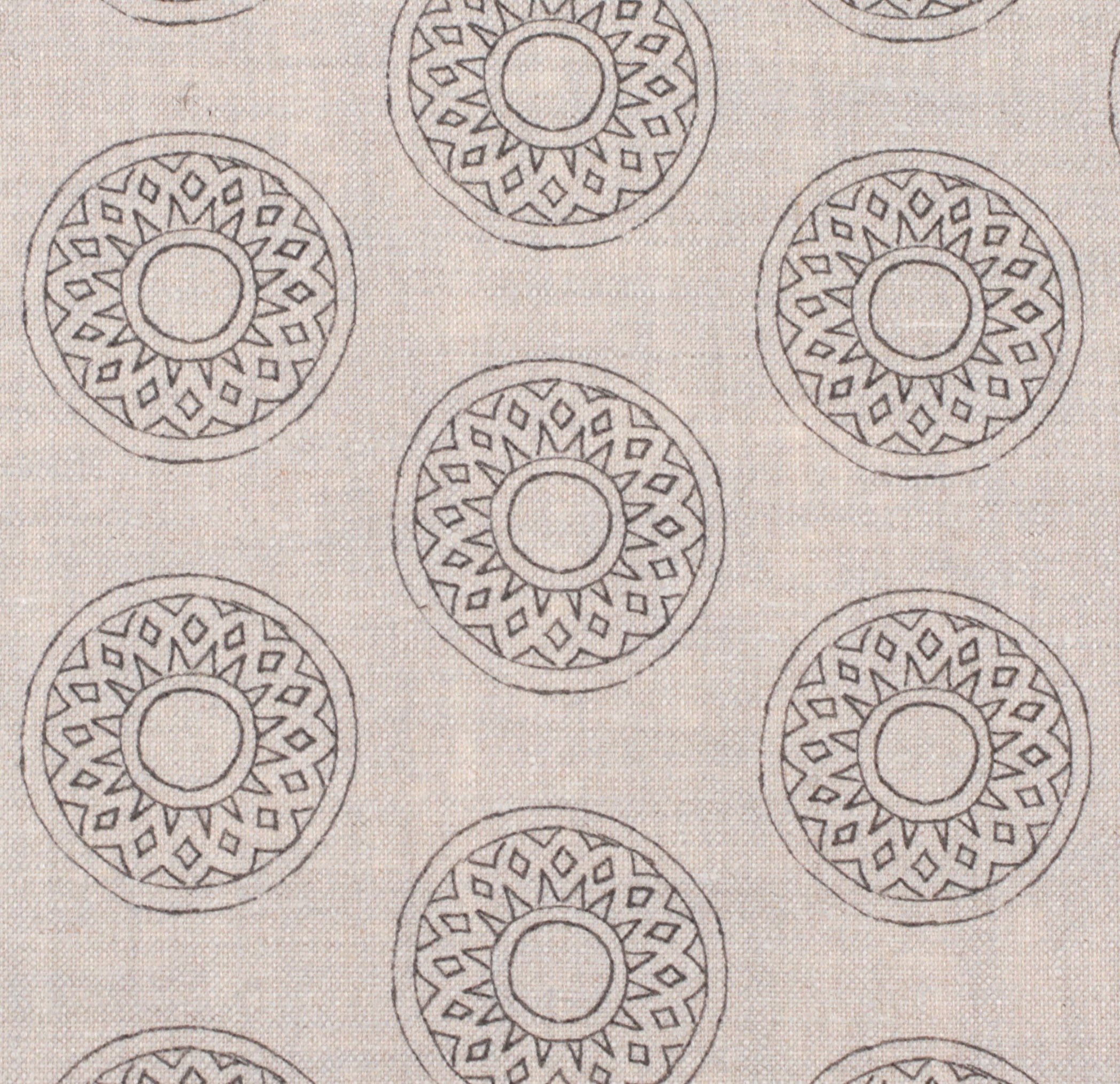 Detail of fabric in a repeating circular geometric print in gray on a cream field.