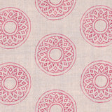 Detail of fabric in a repeating circular geometric print in pink on a cream field.